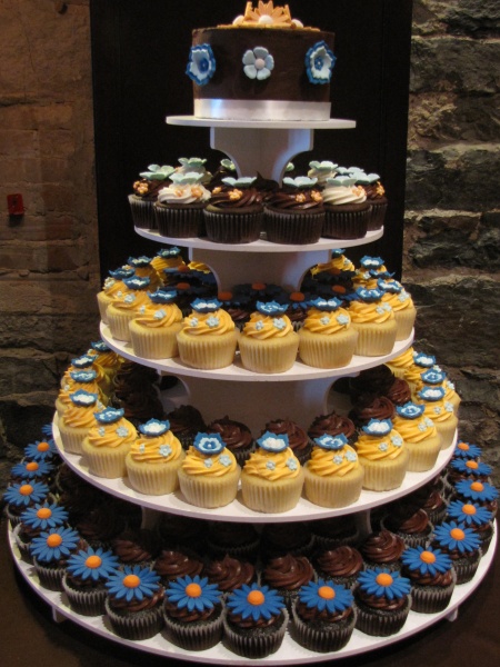a triple layer cake with cupcakes arranged in the center