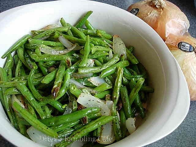 green beans in a white bowl next to a garlic plant