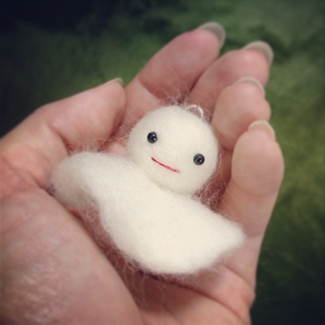 a white stuffed toy sits in the palm of someone's hand