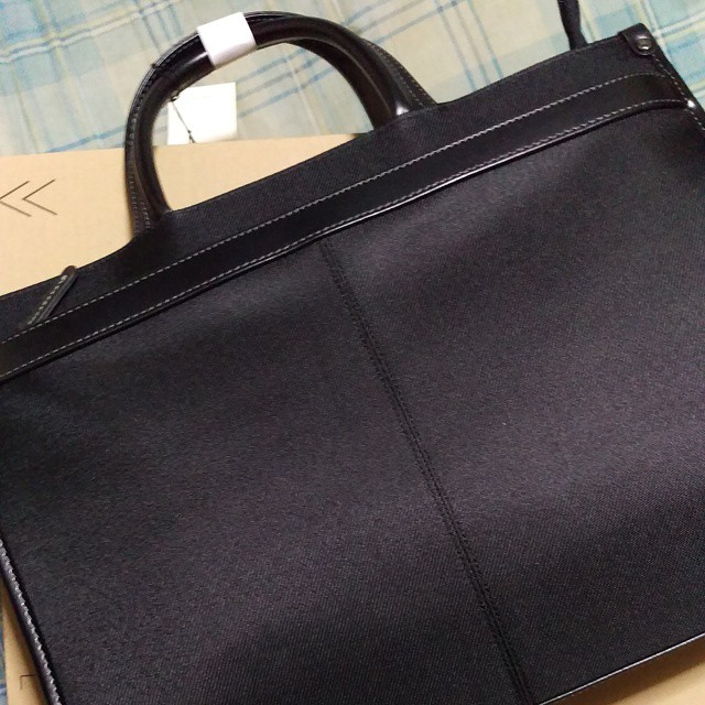 a box holding a black leather briefcase with a white strap