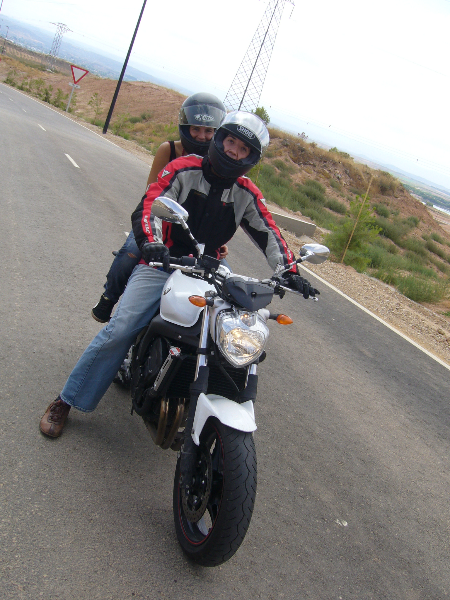 a man and woman riding a motorcycle down a street