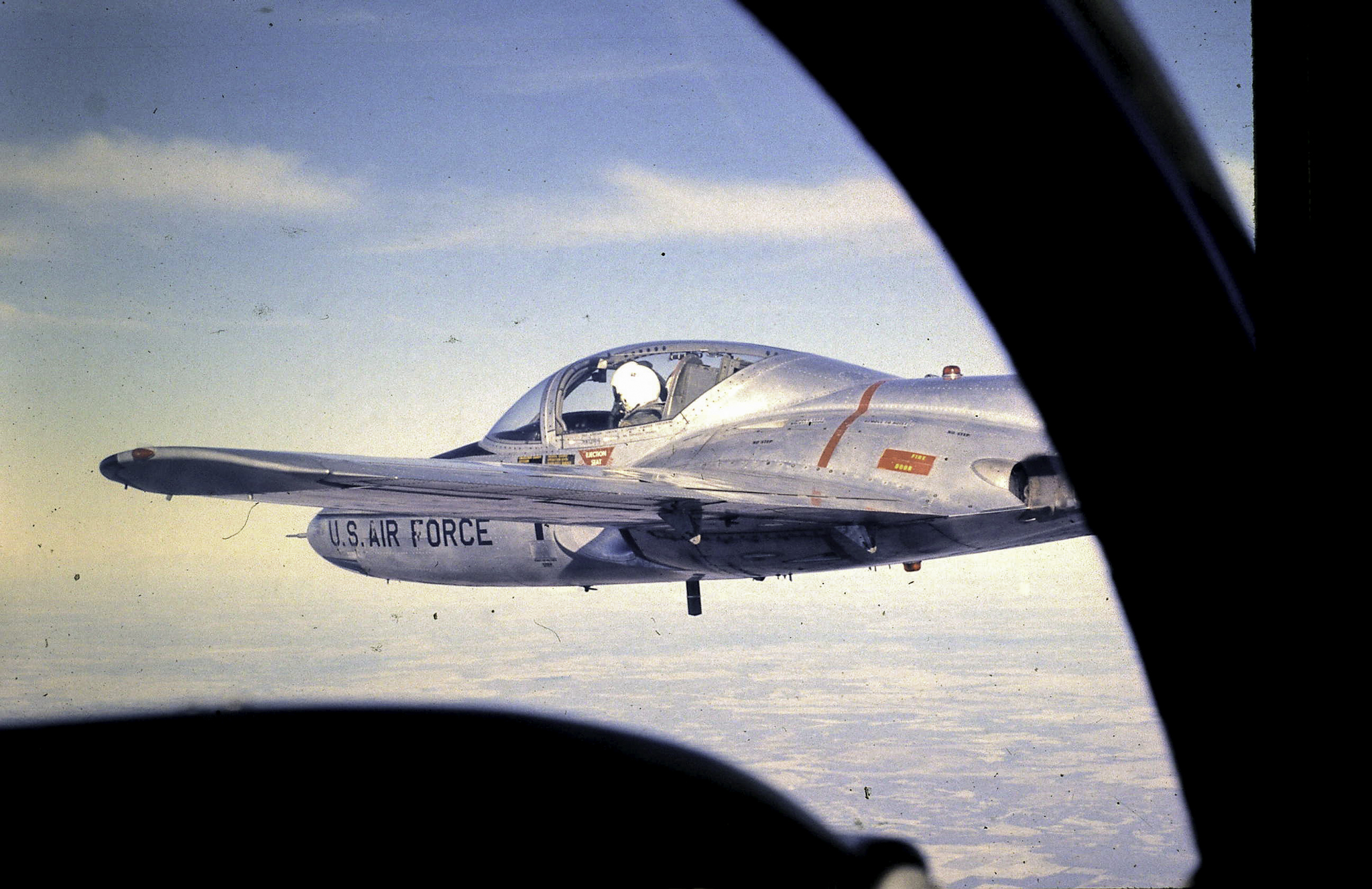 a silver fighter plane flying through the sky