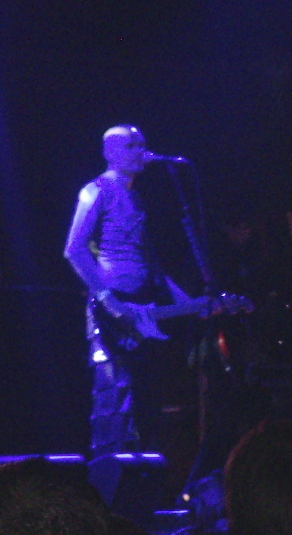 a young man standing in front of a stage on a guitar