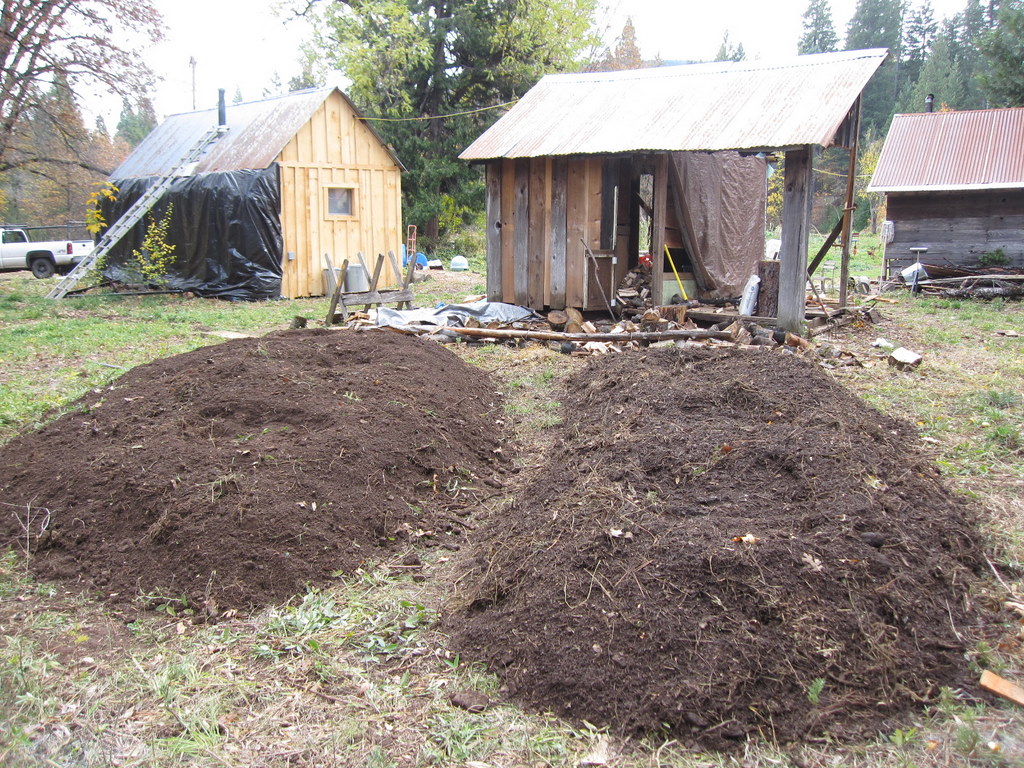 many piles of dirt in a yard near a shack