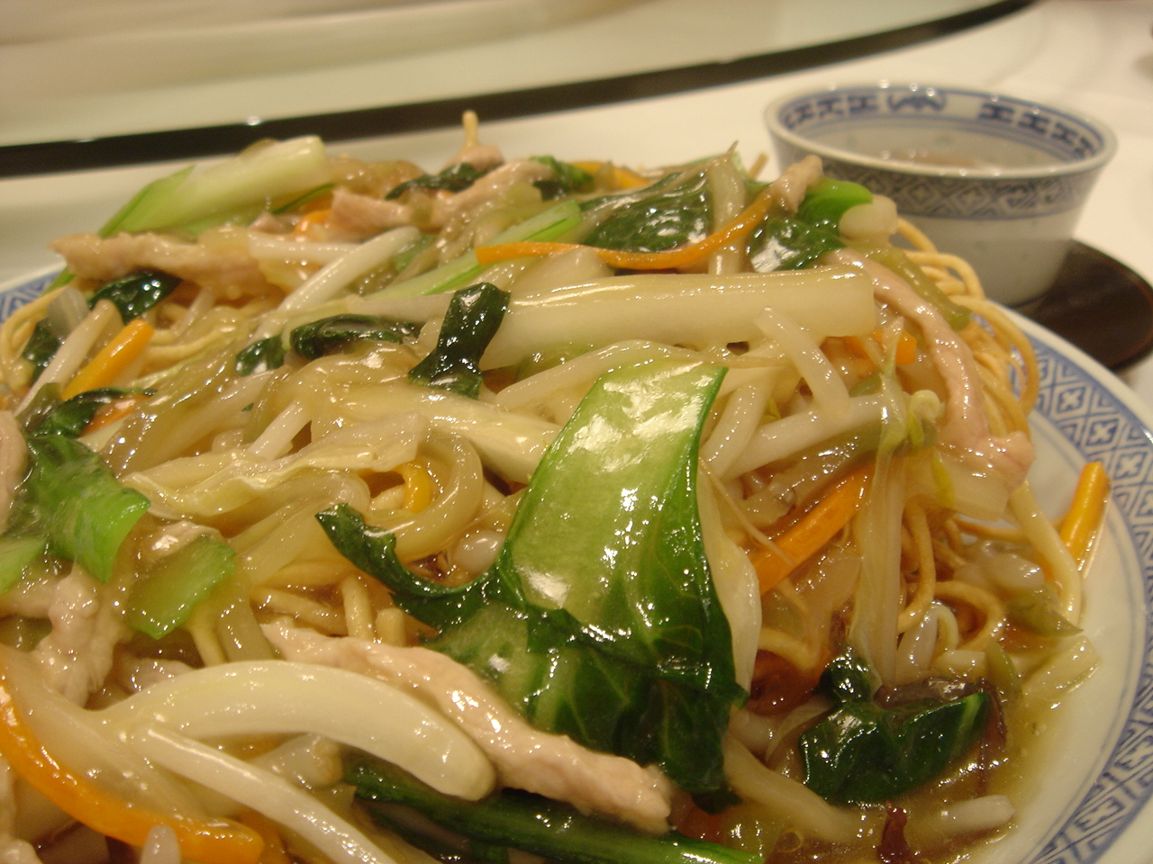 a white and blue plate topped with noodles and vegetables