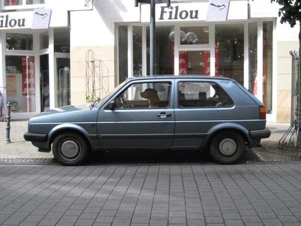 an old, blue car is parked in front of shops