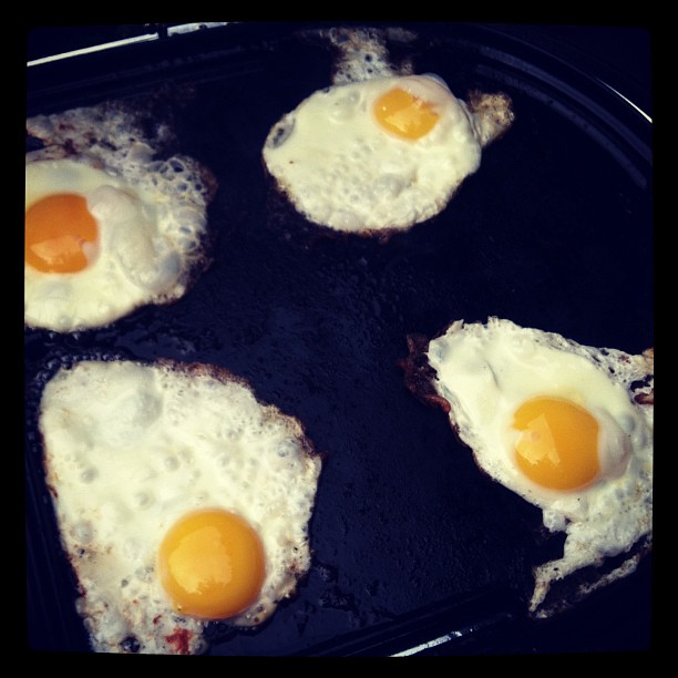 four fried eggs on a griddle in a frying pan