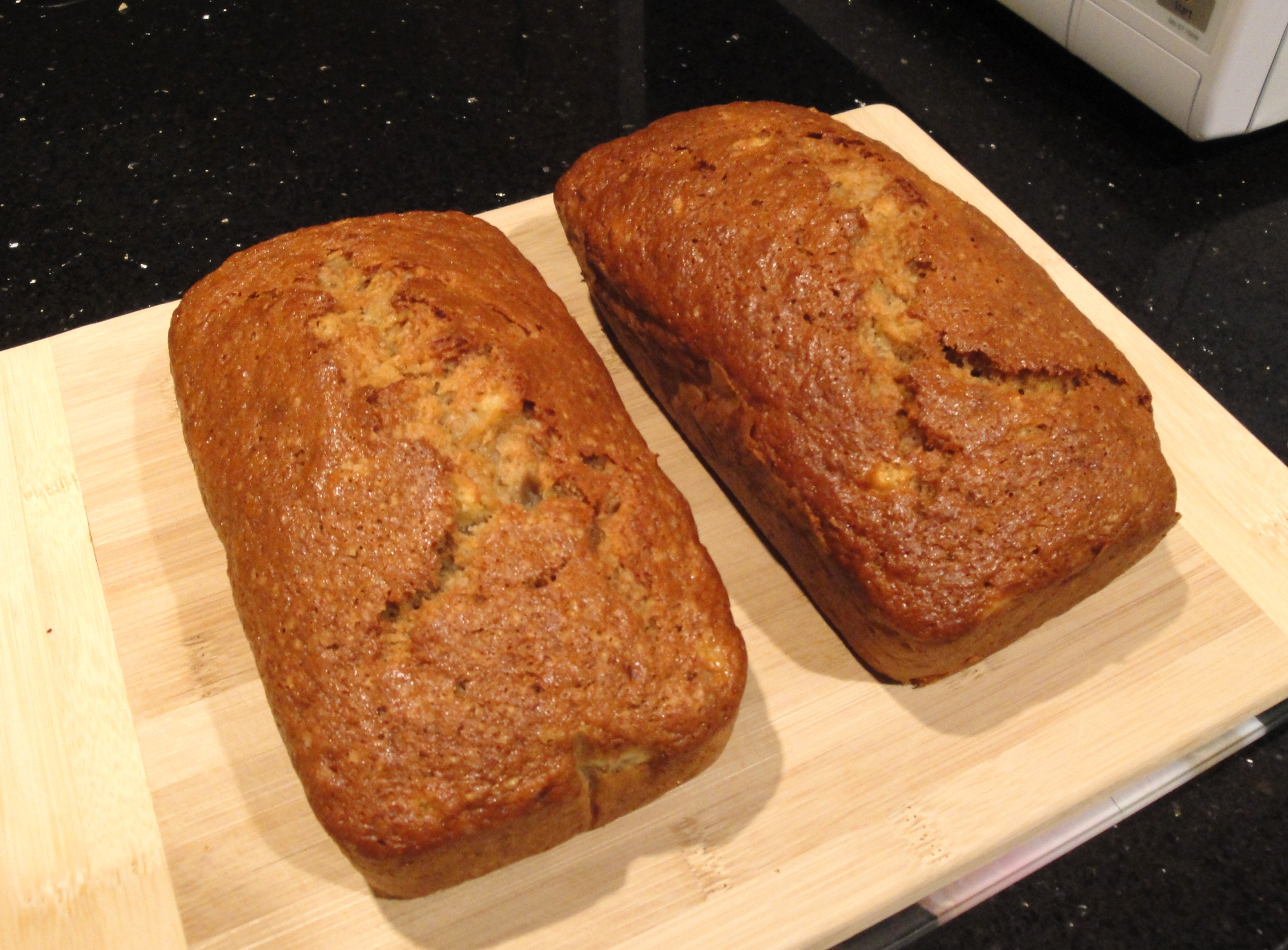 two loafs of bread sitting on a wooden  board