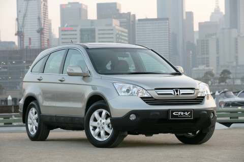 an image of a silver honda cr - v parked in front of a city
