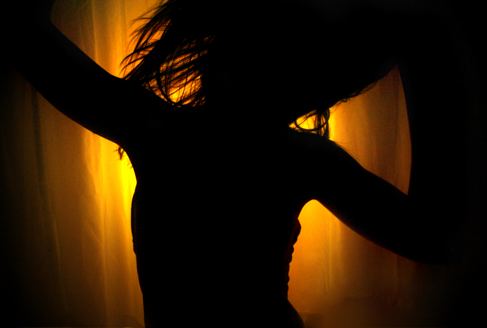 the silhouette of a woman in front of a curtain