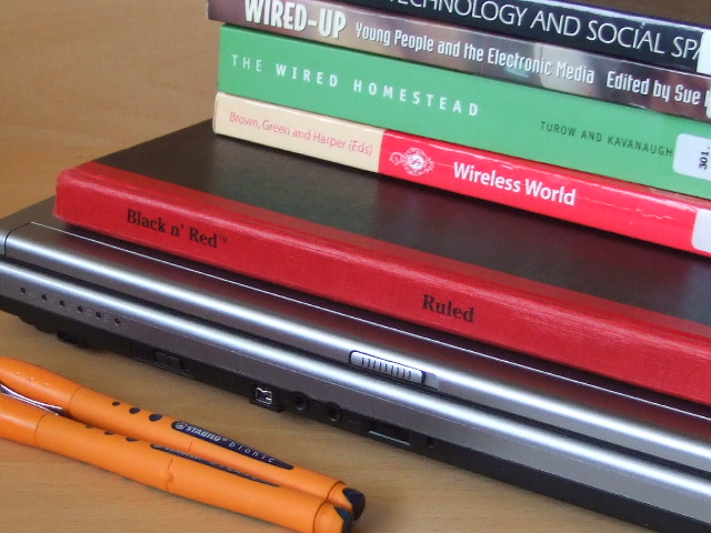 stack of books and a laptop on table