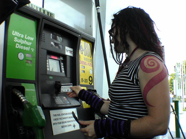 a person wearing gloves at a gas pump filling with gas