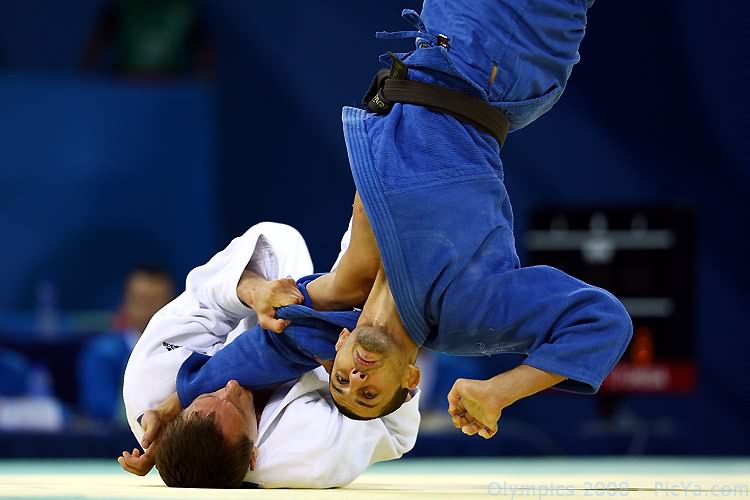 two men in blue and white uniforms are on a wrestling mat