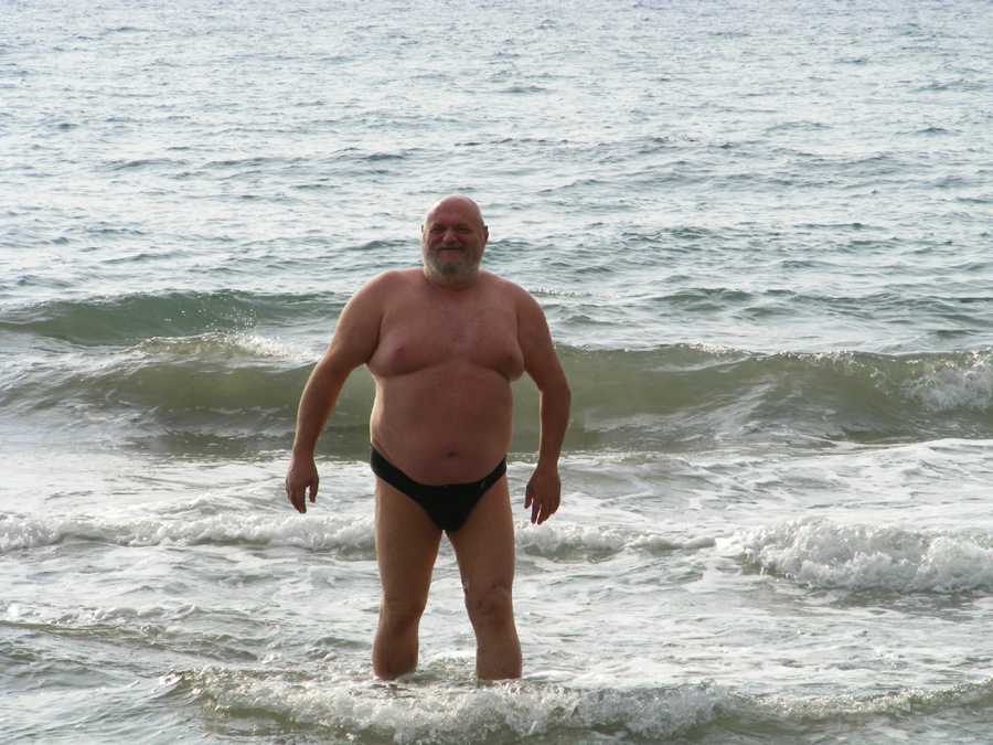 an old man standing in the water on the beach
