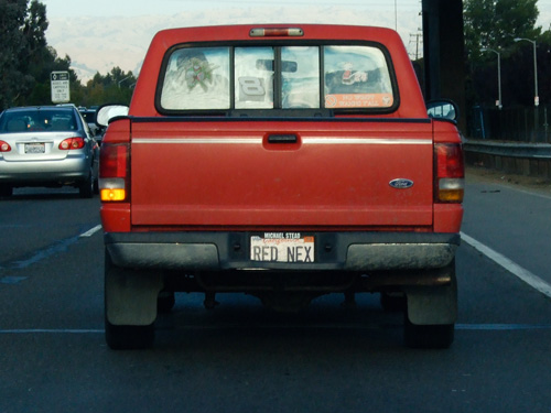 a red pick up truck driving down a street next to a traffic light