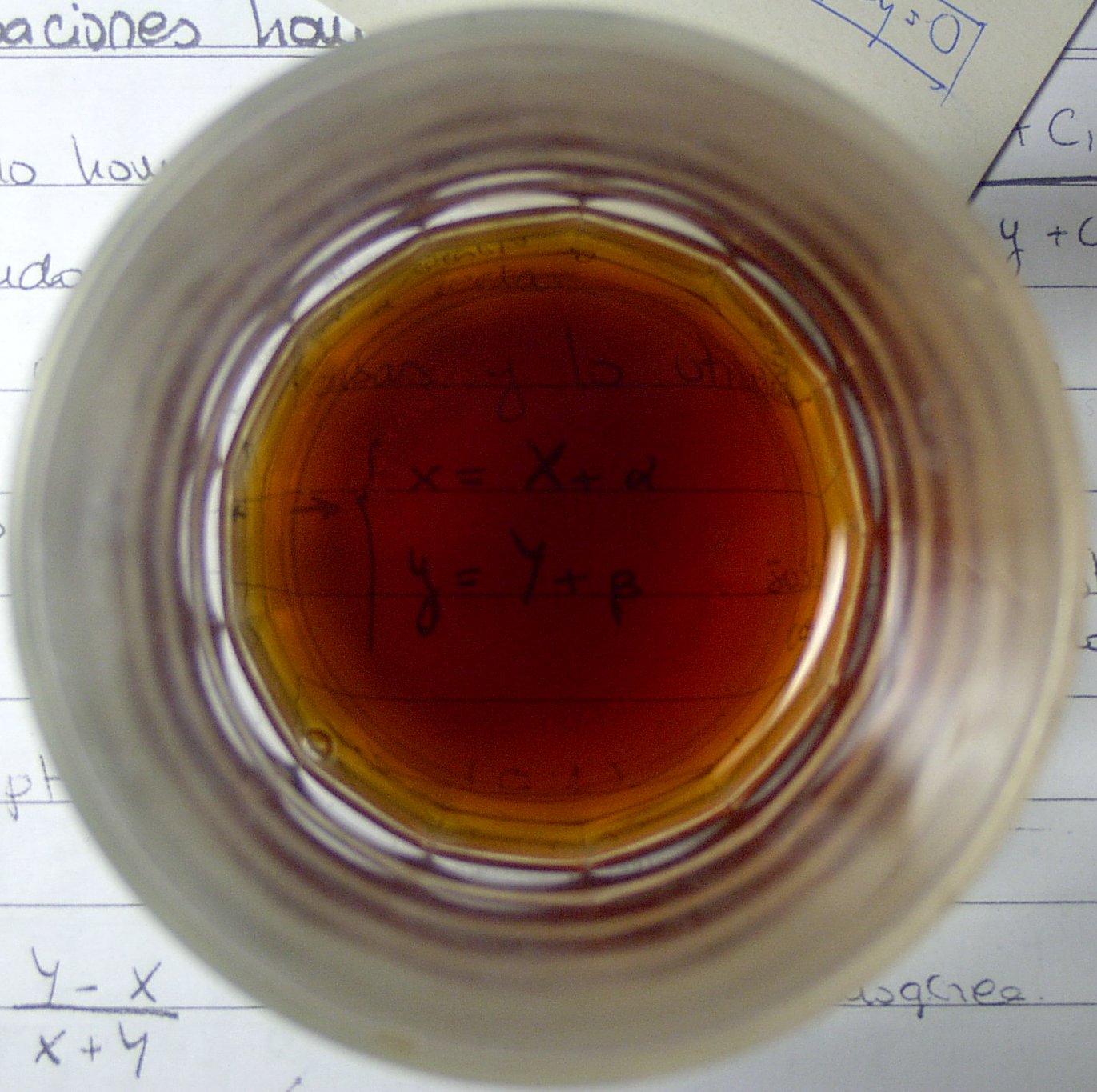 a glass with brown liquid inside of it next to papers