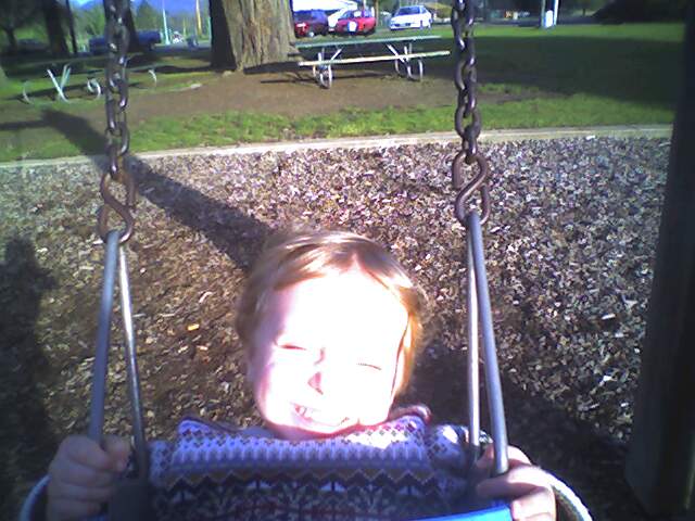 the child has his face near a camera lens in the swings
