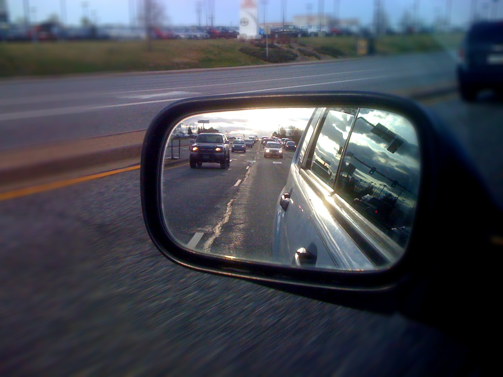 the rear view mirror of the vehicle on a highway