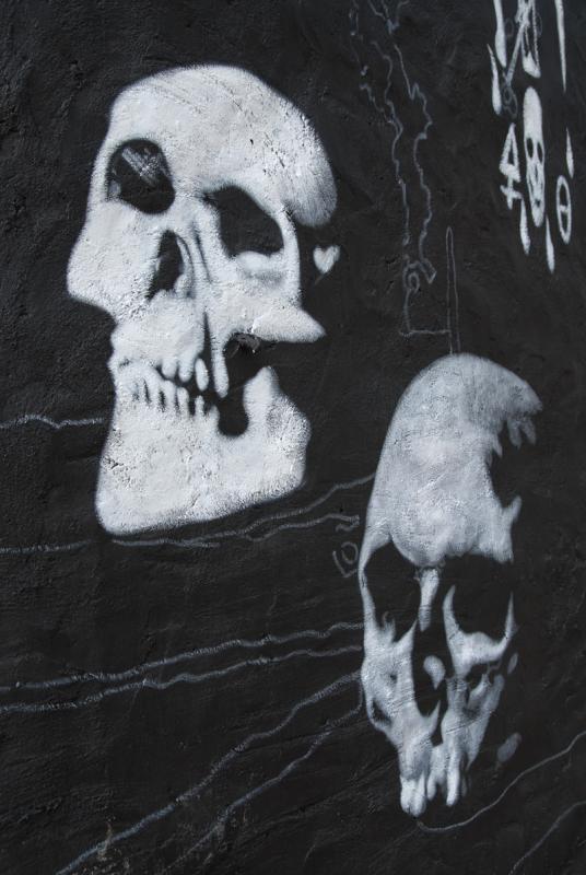 two painted skulls on a wall near one another