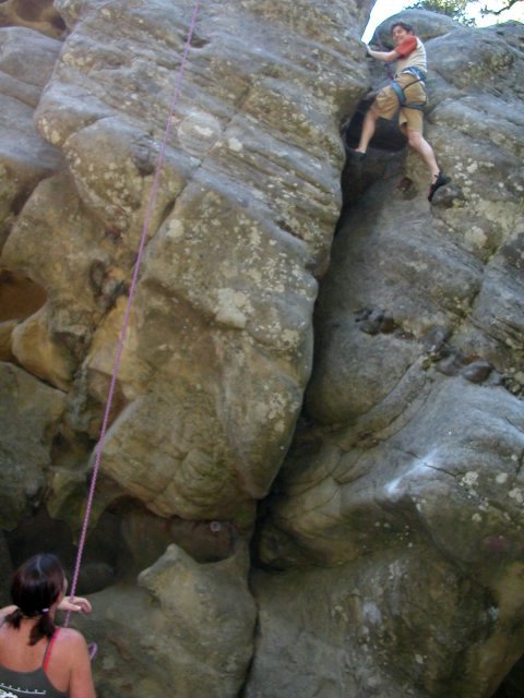 a woman on a rock climbing up a steep slope