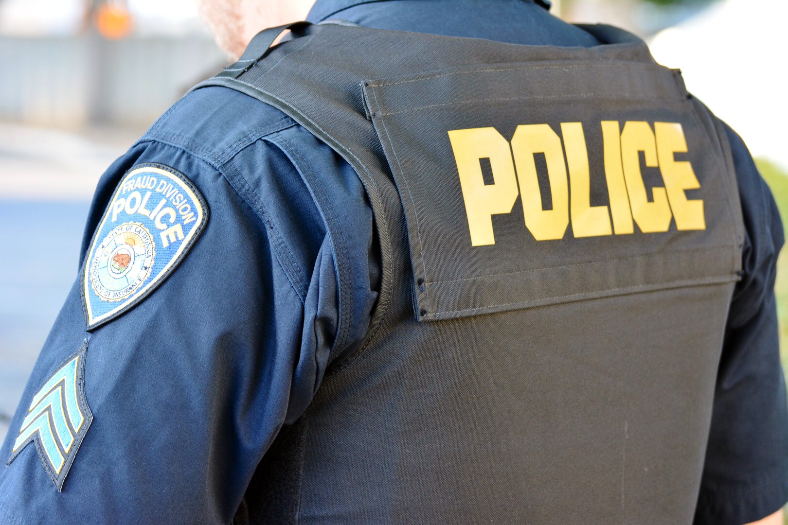 police officer wearing a police patched jacket and standing outside