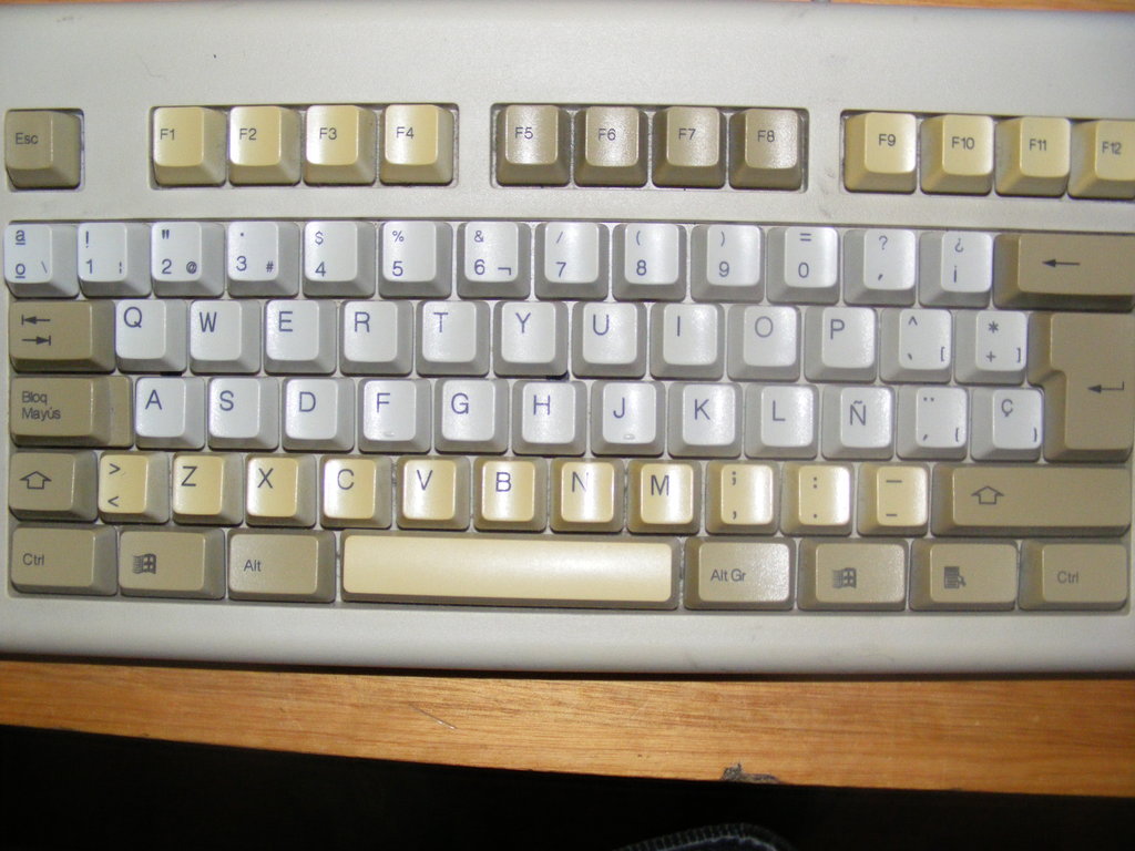 a computer keyboard with white keys sitting on a desk