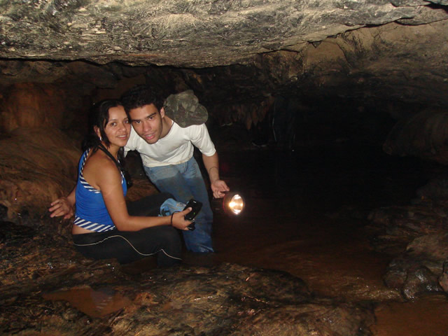 two people are inside a cave holding a flashlight