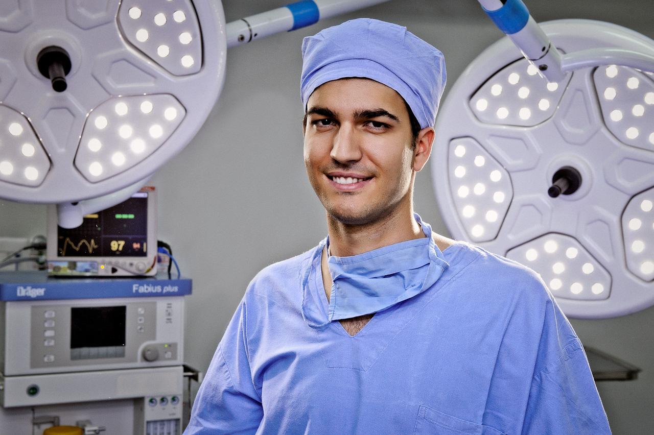 a man wearing scrubs standing near an operating room