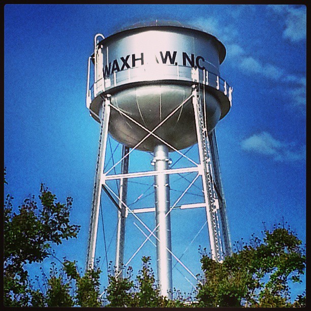 a tall water tower sitting below a blue cloudy sky