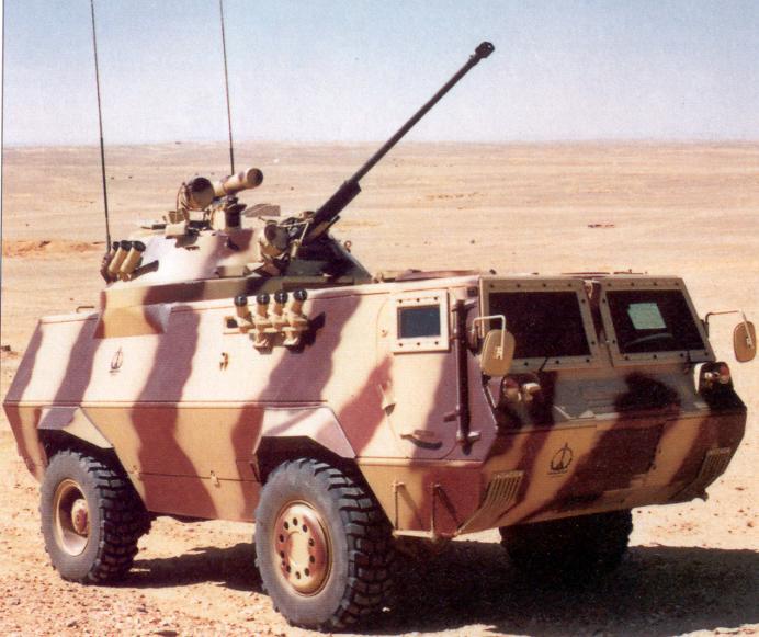 an army vehicle in the desert with a gun strapped to its back