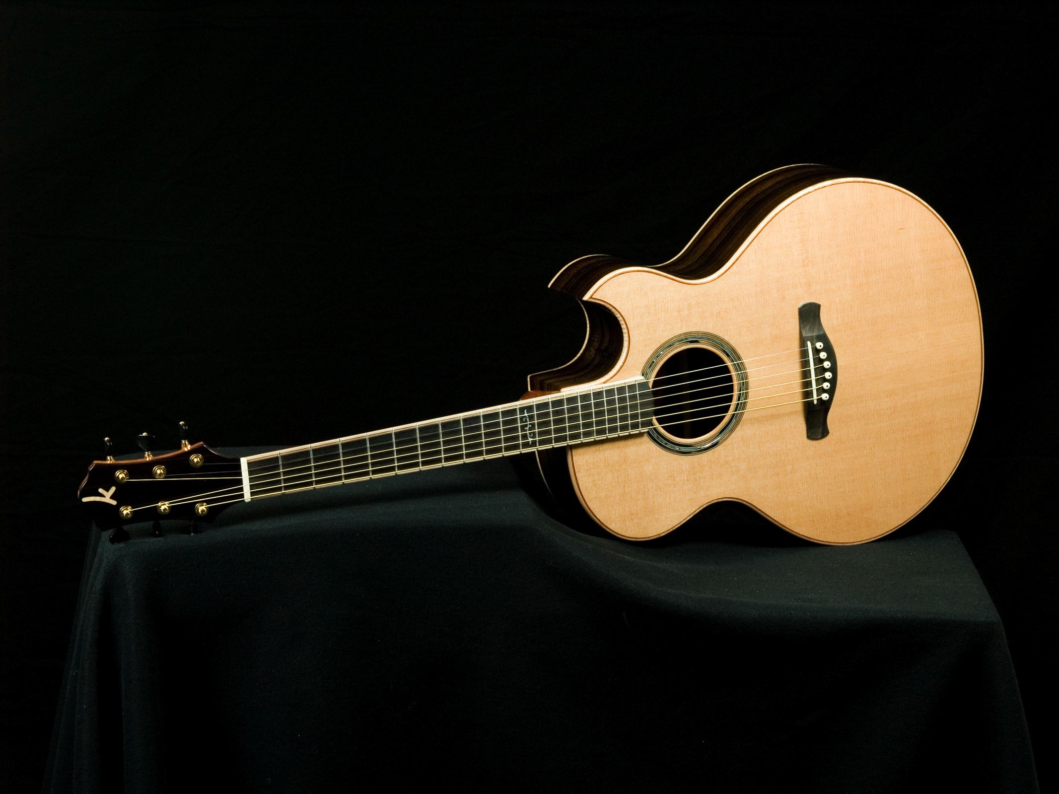 a wooden guitar sitting on a black surface