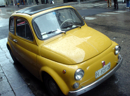 an old yellow car sitting at the curb