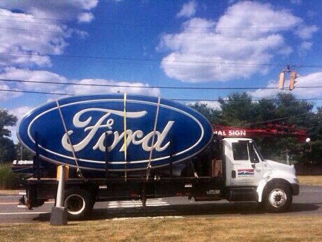 a large blue ford sign on the side of the road