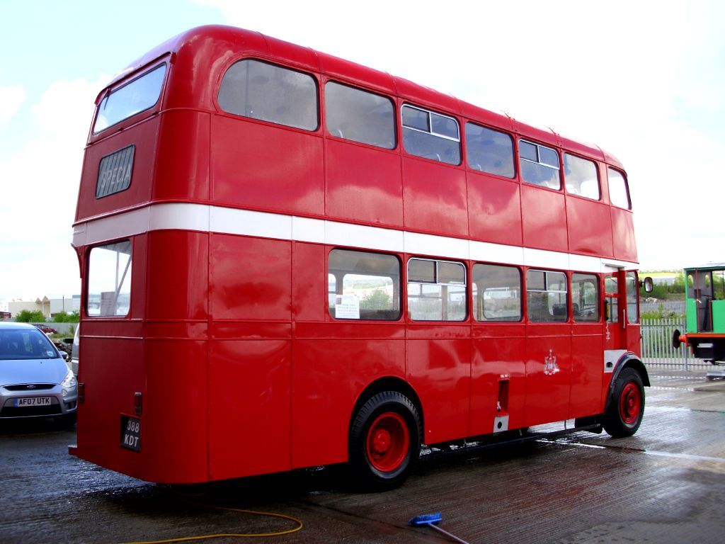 a red double decker bus parked next to other cars
