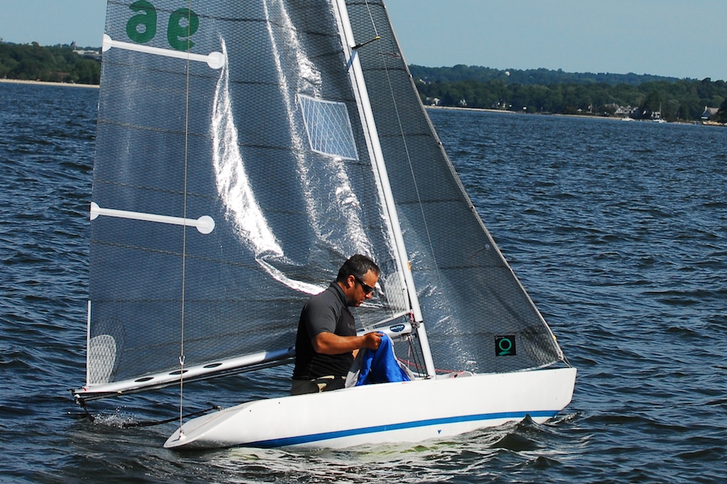 man in sail boat with flag and numbers on side