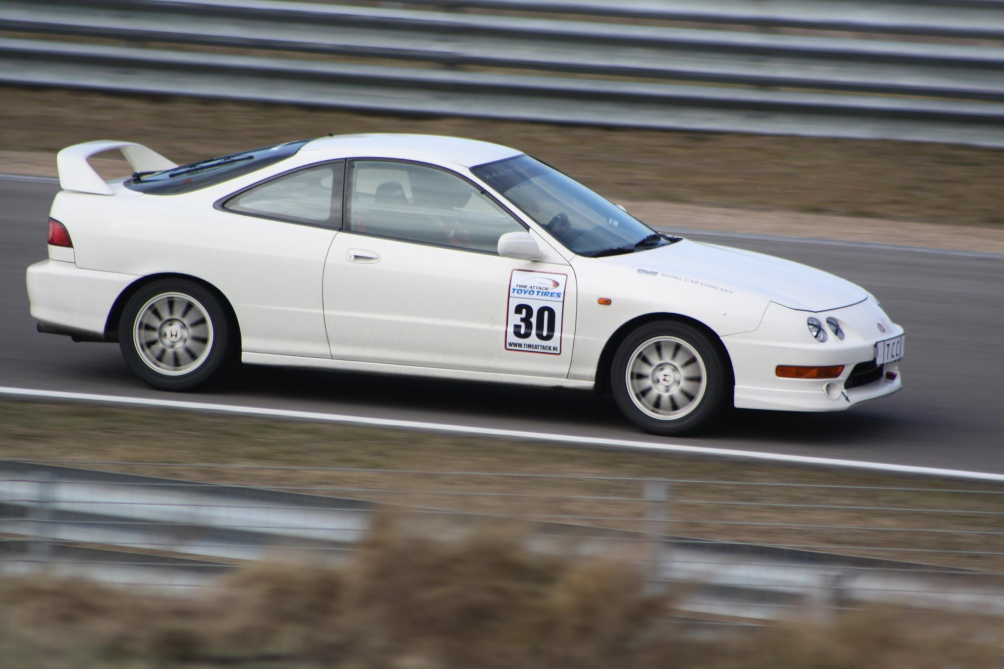 a white compact vehicle drives down a track