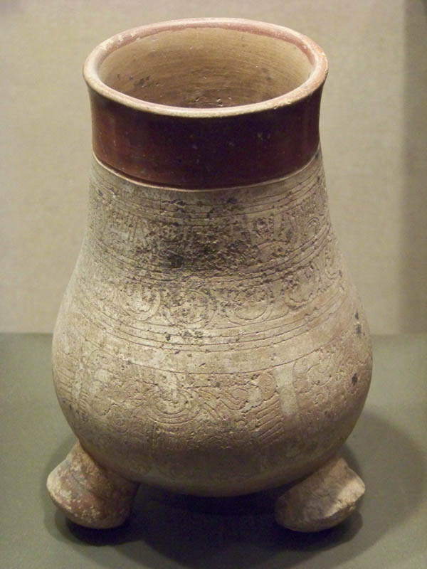 a brown and white clay vase with foot in it