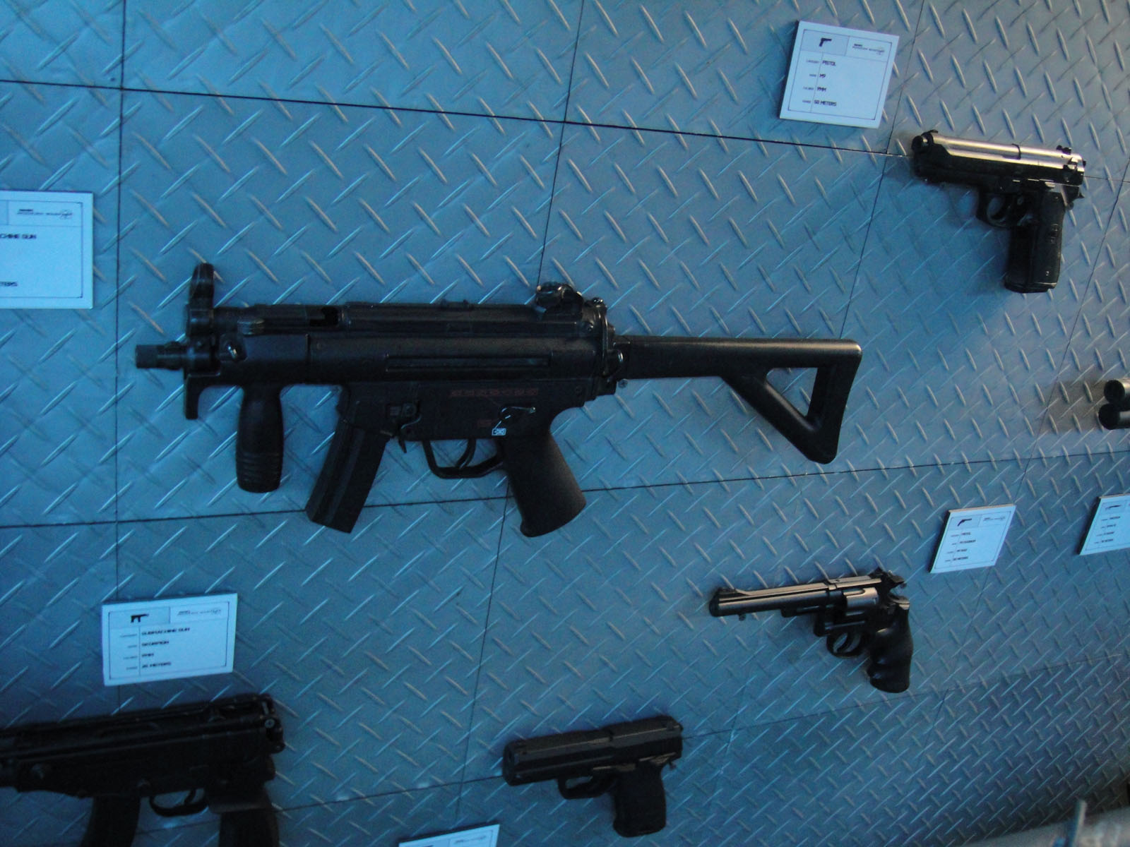 several guns are displayed on blue tile walls