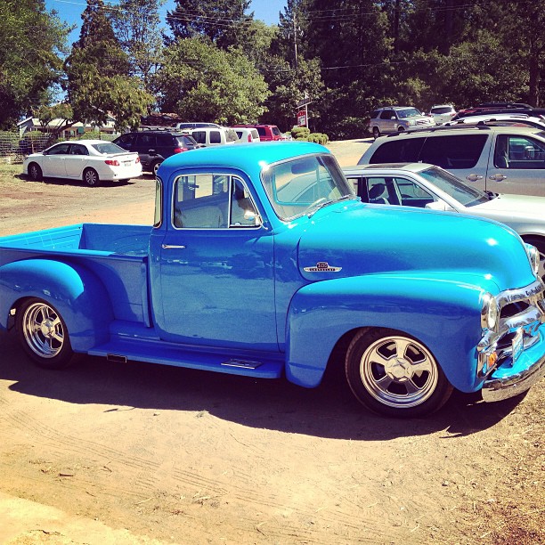 a bright blue truck parked next to many other cars