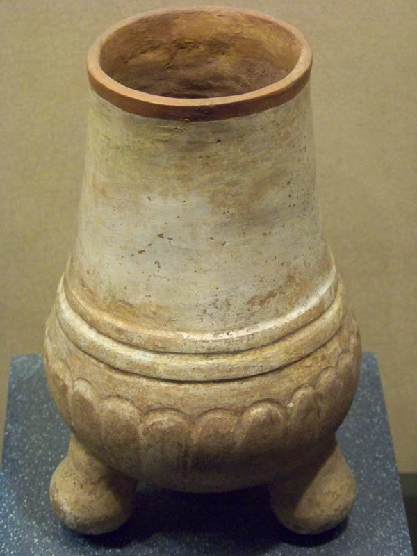 a tall ceramic vase with carved designs on it's base