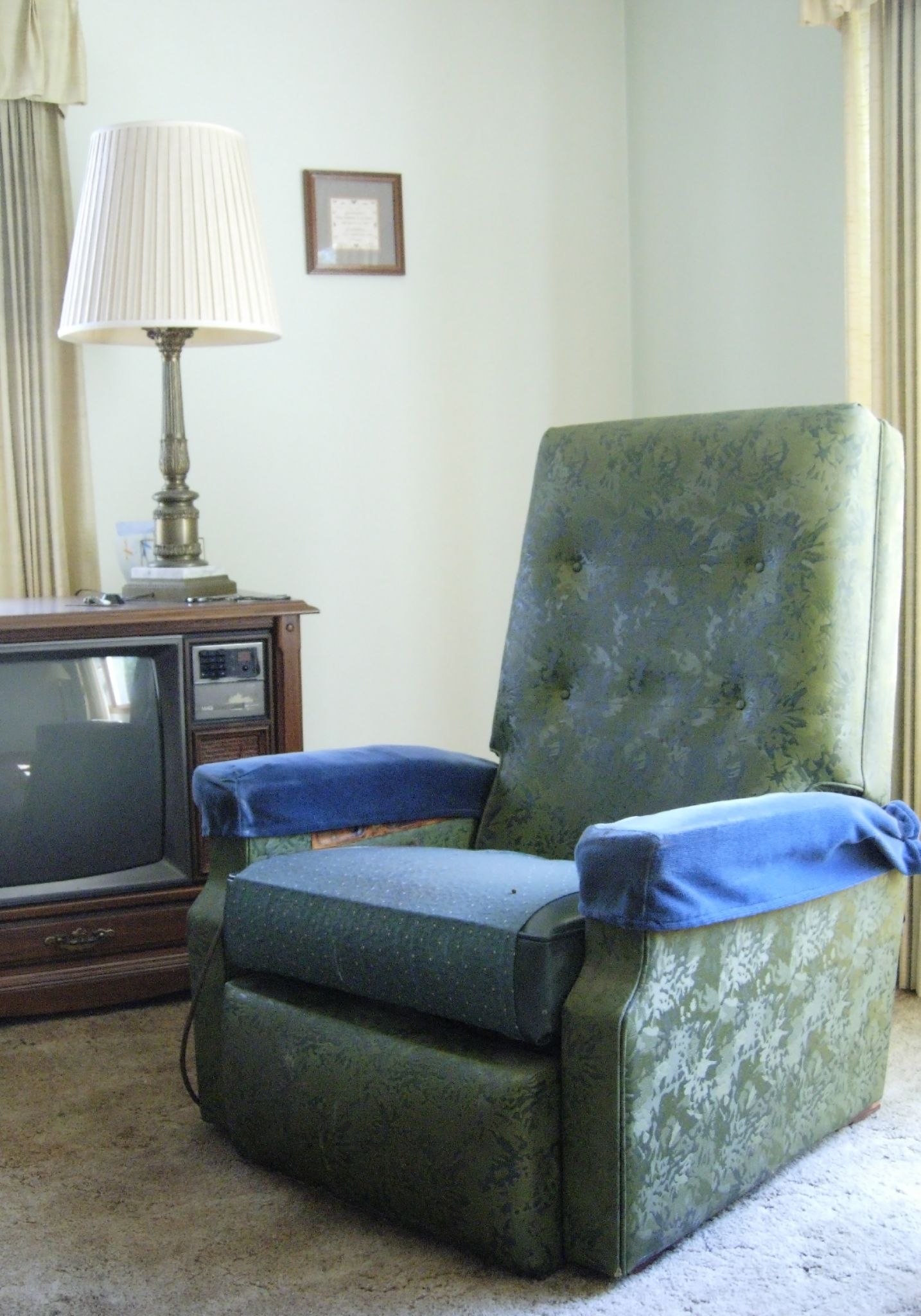a chair sits near a lamp and a tv