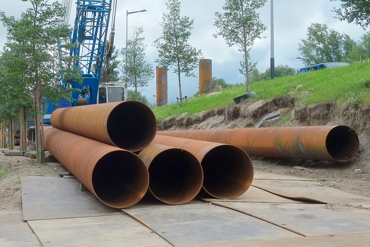 pipe laying on a concrete surface with a crane in the background