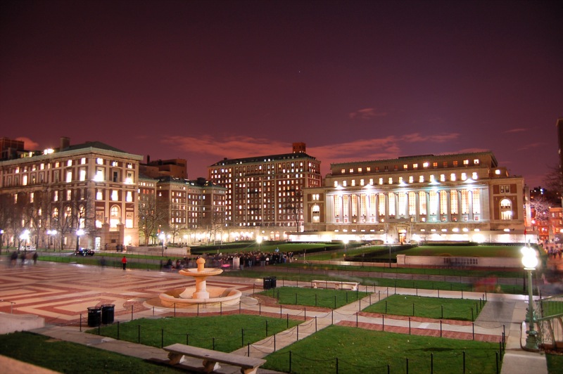 a view of a city at night from across the park