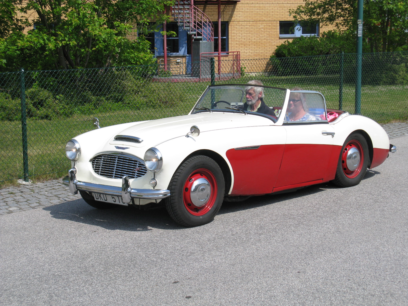 a white and red convertible with a person driving behind