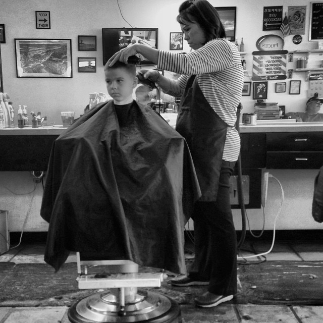 a man is  a boy's hair in a salon