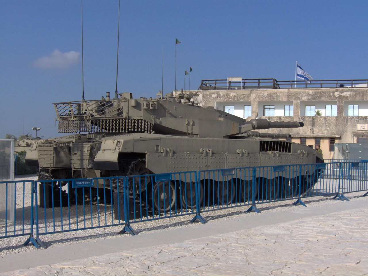 an army tank parked in the sand behind a metal fence