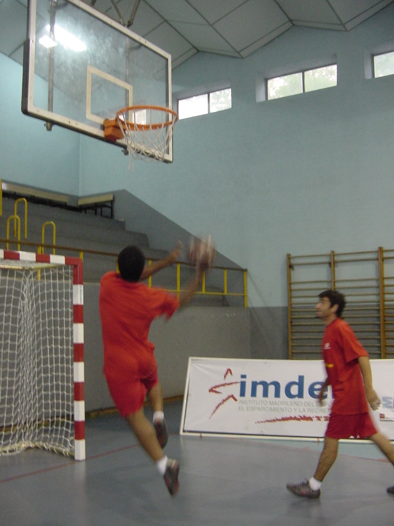 two men playing basketball in an indoor basketball court