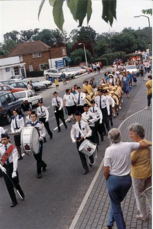 a marching band is lead by man walking across the street