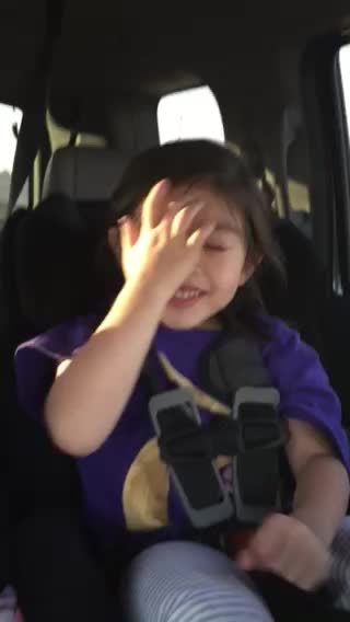 a little girl is holding onto her hand in the back seat