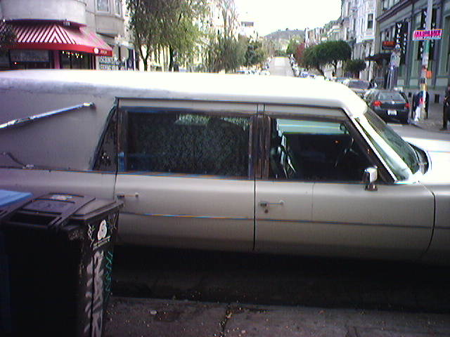 a white car parked in front of a parking meter on a street